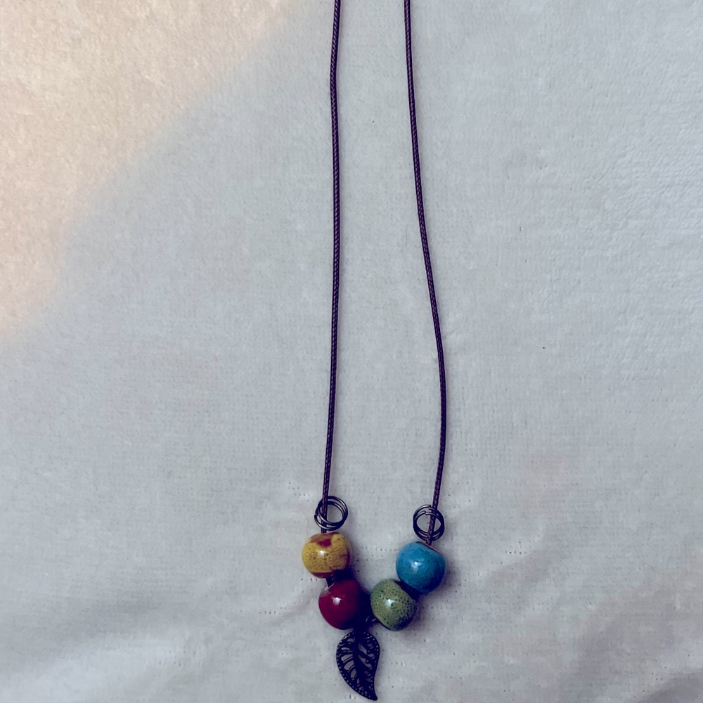 Beaded string necklace with a leaf.